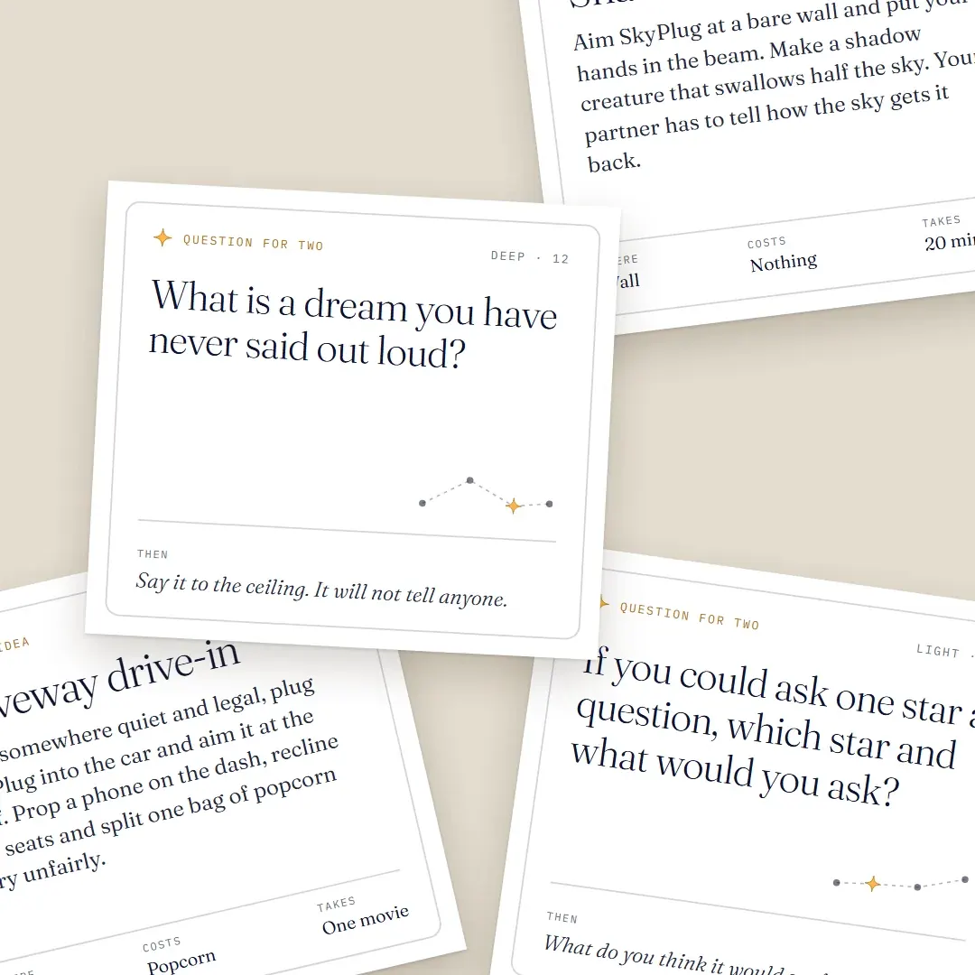 Close-up of three printed cards: a question card asking what dream you have never said out loud, a date idea card for a driveway drive-in.