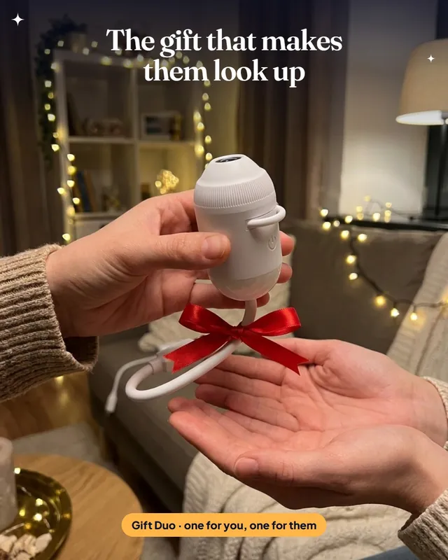 Render of one person handing SkyPlug with a red ribbon to another person in a cozy room with fairy lights.