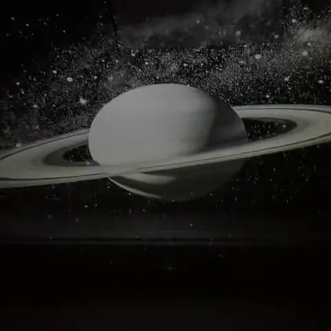 Still from the seller's video: Saturn with its rings projected in white light on a dark ceiling, stars around it.
